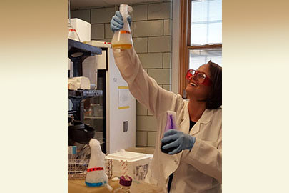 Female researcher holding up a beaker.